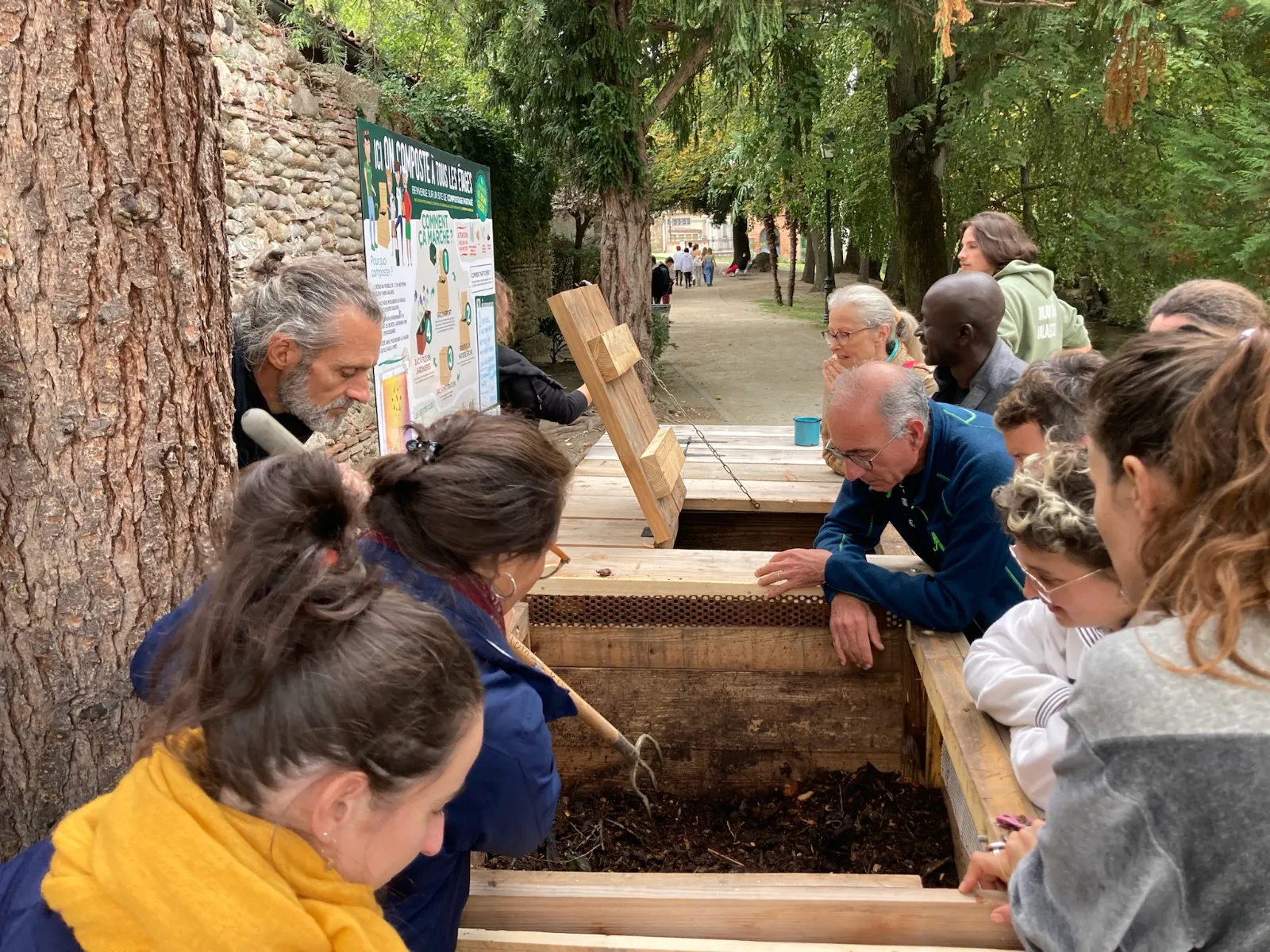 Atelier de sensibilisation au compostage : habitants et enfants observent le contenu d'un bac de compostage