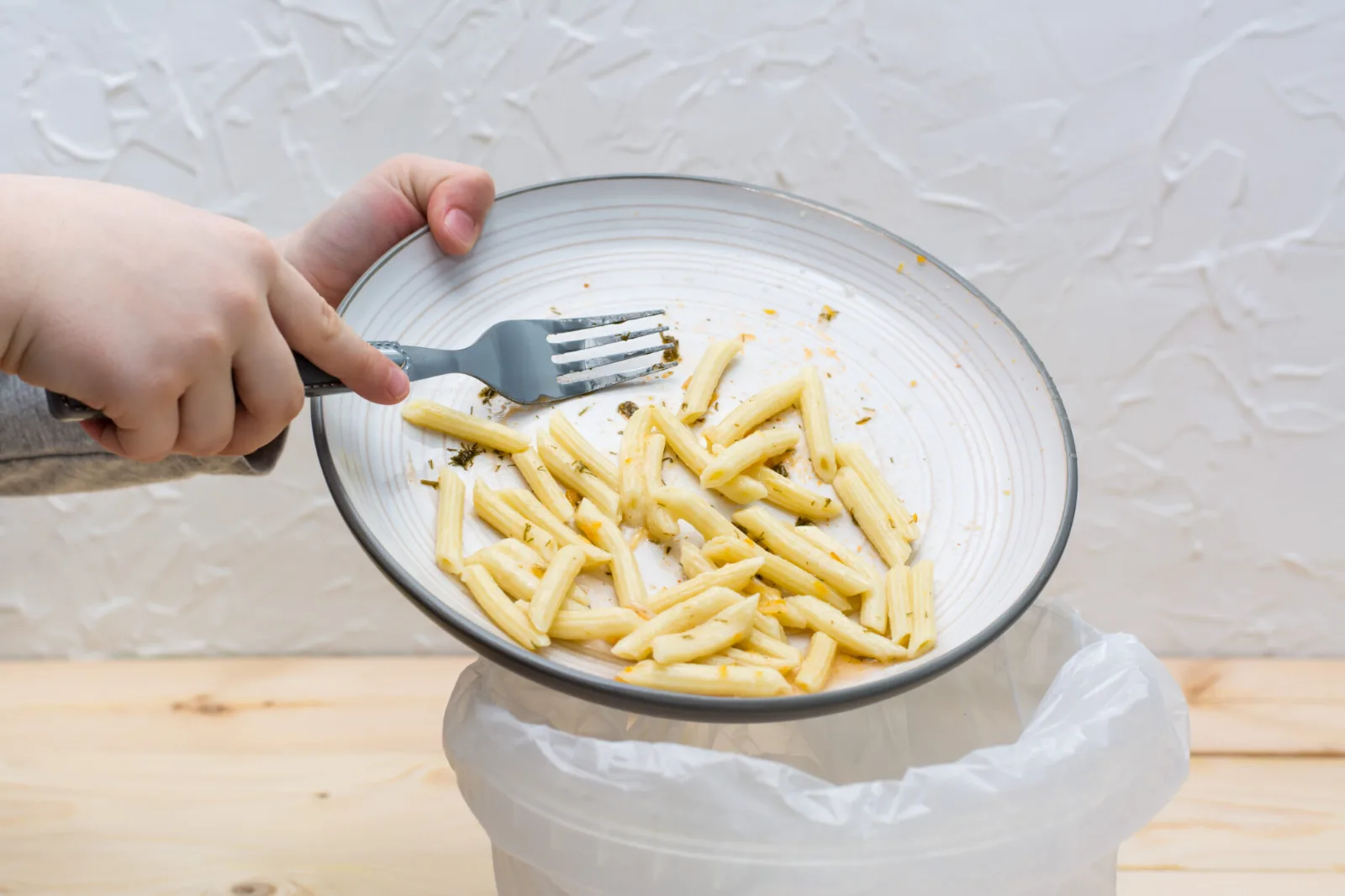Restes de repas raclés d'une assiette dans un bac à biodéchets
